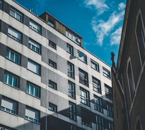 A vertical shot of a gray and white building with windows under a blue sky